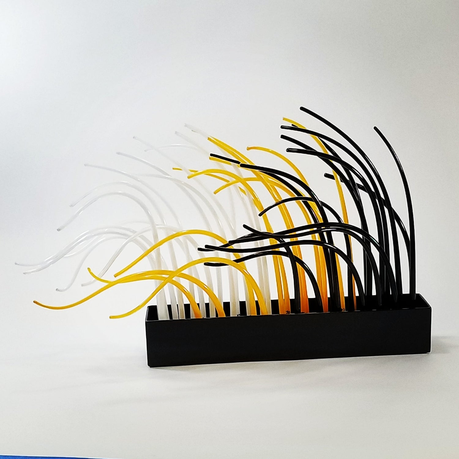 A glass sculpture with colorful tendrils sits on a white background
